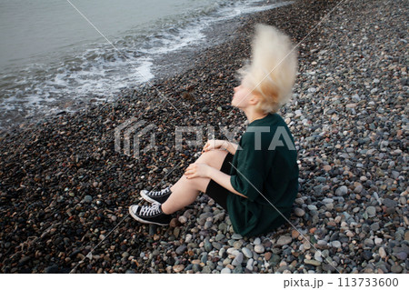 Portrait of young girl with short blonde bob hair and green dress on cold sea beach Portrait of young girl with short blonde bob hair and green dress on cold sea beach 113733600