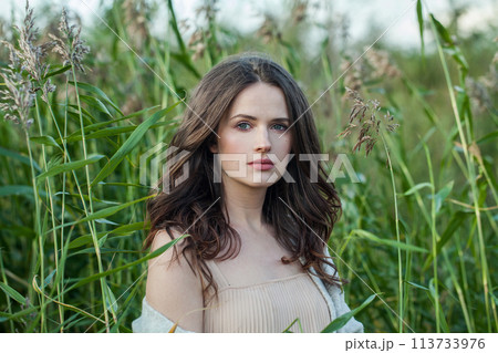 Relaxing healthy young brunette woman with fresh clear skin and long dark brown hair outdoors 113733976