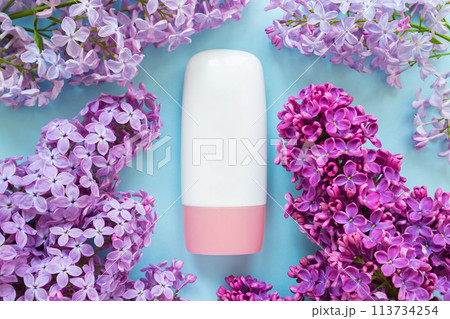 cosmetic moisturizer tube bottle with pink screw cap, lilac flowers a lot on blue background. cream, gel, skincare, shampoo, lotion, balsam, toothpaste. blank tube template mockup, bottle container cosmetic moisturizer tube bottle with pink screw cap, lilac flowers a lot on blue background. cream, gel, skincare, shampoo, lotion, balsam, toothpaste. blank tube template mockup, bottle container 113734254