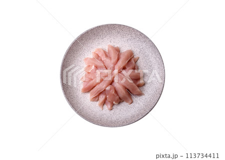 Slices of raw chicken or turkey fillet with salt, spices and herbs 113734411