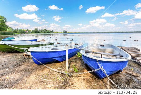 Plastic pleasure boats are moored on the shore of the lake 113734528