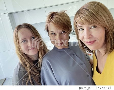 Cute mid adult women mother and her daughters making a selfie using smart phone at home 113735251