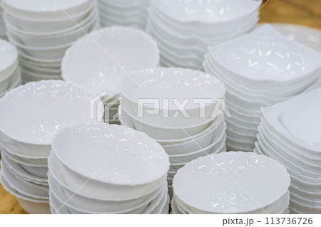 A stack of white mugs and plates in the store for sale. White and clean dishes A stack of white mugs and plates in the store for sale. White and clean dishes 113736726