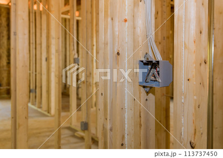 An electrical switch box plastic mounted a wires on wooden frame beams on wall An electrical switch box plastic mounted a wires on wooden frame beams on wall 113737450