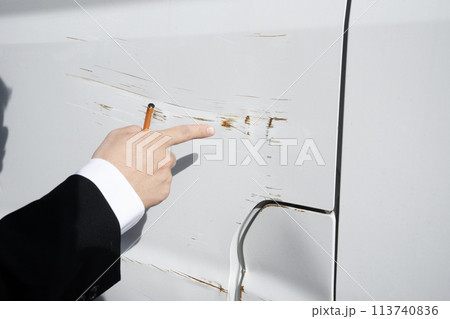 自動車の傷を指差す作業員の手元 113740836