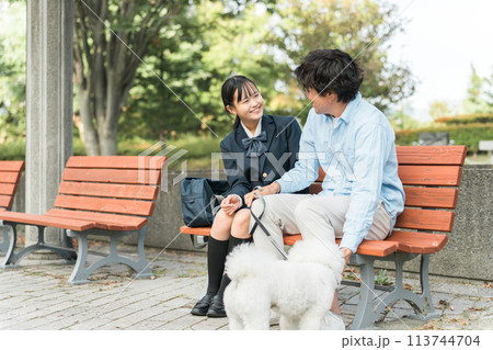公園のベンチに座る犬の散歩をする愛犬家の親子・娘・父親 公園のベンチに座る犬の散歩をする愛犬家の親子・娘・父親 113744704
