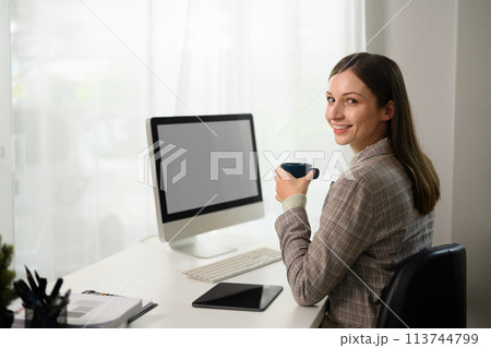 Millennial businesswoman drinking hot coffee while working online from home office 113744799