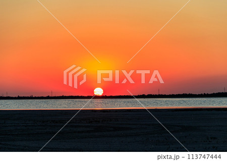 Beautiful orange sunset over a salt lake Beautiful orange sunset over a salt lake 113747444