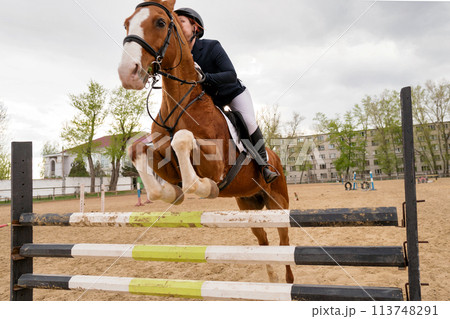 Equestrian event, rider and horse mid-obstacle course. 113748291