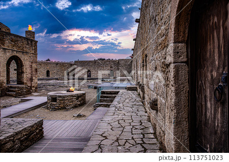 Stone building with wooden door and stairs in a city landscape with cloudy sky 113751023