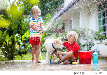 Kids wash dog in summer garden. Water hose fun. Kids wash dog in summer garden. Water hose fun. 113751048