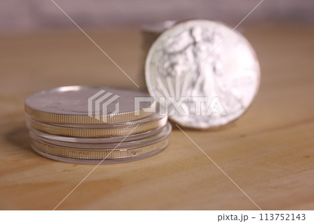 Stacks of American Silver Eagle Coins on Wooden Table Stacks of American Silver Eagle Coins on Wooden Table 113752143