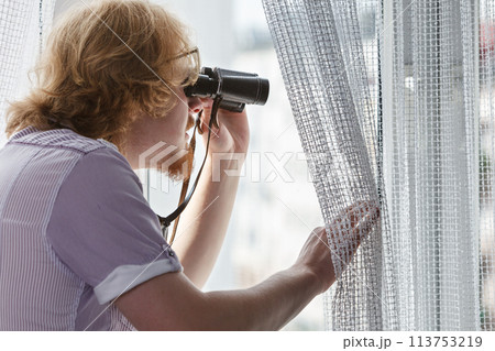 Man with binoculars spying on neighbors Man with binoculars spying on neighbors 113753219