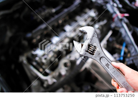 Adjustable wrench or adjustable spanner in a car mechanic hand with car engine blurred background Adjustable wrench or adjustable spanner in a car mechanic hand with car engine blurred background 113753250
