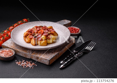 Grilled potatoes cut into slices with hunting sausages with garlic, onion 113754276