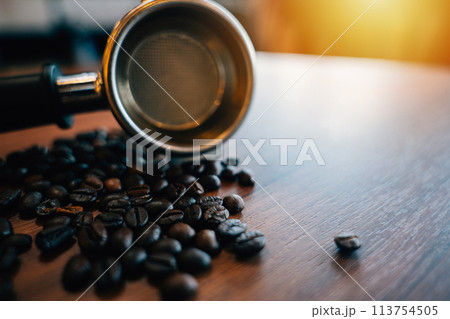 Coffee beans and tamper on a modern table. Metal equipment for espresso preparation. Organic beans restaurant setting with mocha cup gourmet refreshment. 113754505