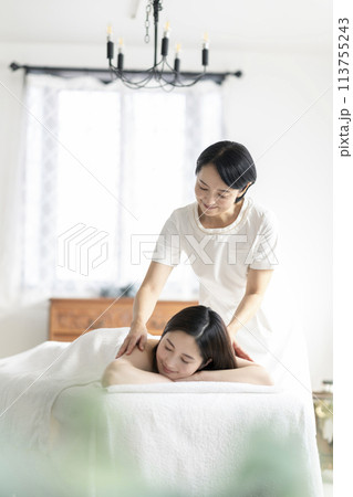 エステサロン　施術を受ける若い女性とミドルのセラピスト 113755243