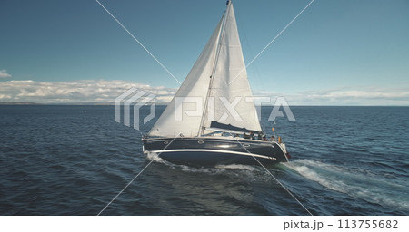 Slow motion closeup of sail luxury yacht at ocean bay aerial. Boat race at open sea. Sailboat regatta at Brodick harbor, Arran Island, Scotland, Europe. Seascape with sun reflection at summer cruise 113755682