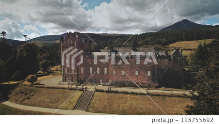 Scotland Brodick Castle aerial front shot: heritage of Scottish. Historical landmark of Arran Island with majestic landscape. Parks and garden near building under cloudy sky. Scenery view 113755692