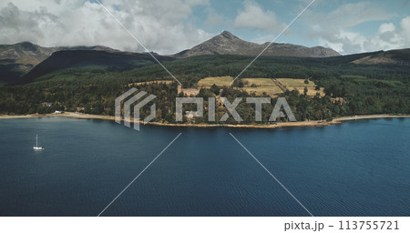 Scotland mountain Goatfell landscape aerial panoramic view at Brodick Harbour, Arran Island. Majestic Scottish nature scenery of forests, meadows and medieval castle. 113755721