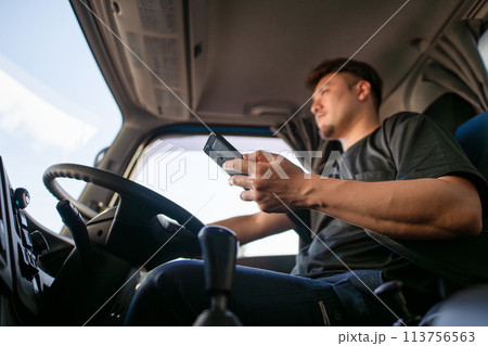 スマートフォンを操作しながら運転をするトラックドライバー 113756563