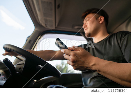 スマートフォンを操作しながら運転をするトラックドライバー 113756564