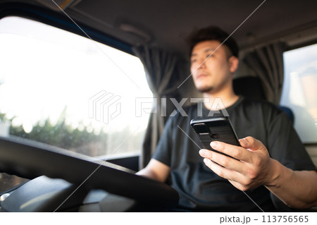 スマートフォンを操作しながら運転をするトラックドライバー 113756565