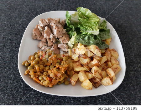 Homemade grilled chicken with french fries, green salad and pea stew served on a white plate 113758199