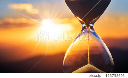 Close-up of a Transparent Hourglass with Blurry Sky at Sunset or Sunrise - Generative Ai 113758603