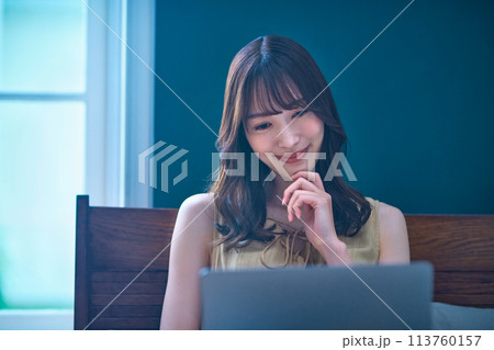 寝室でパソコンを操作する若い女性 寝室でパソコンを操作する若い女性 113760157