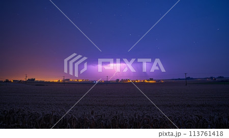 Blue sky illuminated by a spectacular purple lightning bolt, environmental and high voltage themes, night setting, intense and striking display 113761418