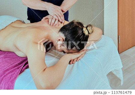 Back pain of young Caucasian woman is treated by a trained massage therapist using deep tissue massage. 113761479