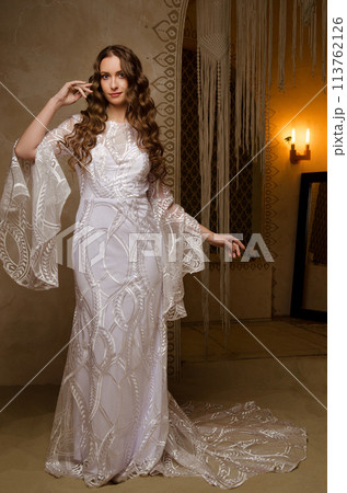 Beautiful girl posing in a boho style wedding dress Beautiful girl posing in a boho style wedding dress 113762126