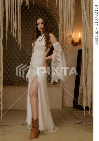 Beautiful girl posing in a boho style wedding dress Beautiful girl posing in a boho style wedding dress 113762153