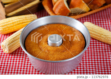 corn cake in the pan baking form on rustic wooden table. Typical Brazilian party food. Selective focus corn cake in the pan baking form on rustic wooden table. Typical Brazilian party food. Selective focus 113762978