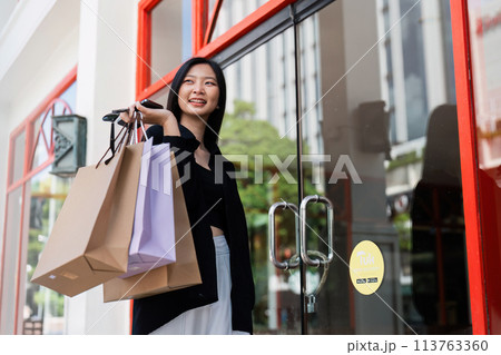 Young asian woman in shopping. Fashion woman in black with shopping bag walking around the city after shopping. Black friday 113763360