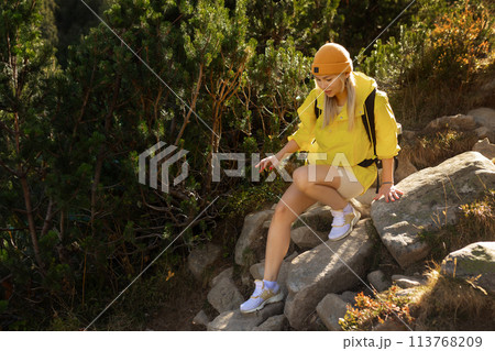 Excited woman walking through landscape outdoors. An active girl enjoys her vacation in the forested mountains. Smiling tourist on a hike. A joyful explorer going on a tourist adventure. Excited woman walking through landscape outdoors. An active girl enjoys her vacation in the forested mountains. Smiling tourist on a hike. A joyful explorer going on a tourist adventure. 113768209