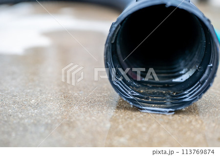 Selective focus on the front opening of a residential sump pump discharging water from the end of a flexible black hose Selective focus on the front opening of a residential sump pump discharging water from the end of a flexible black hose 113769874