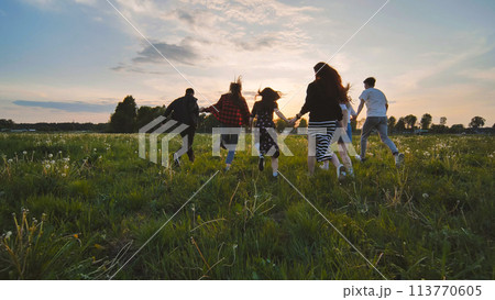 Merry friends run off into the sunset holding hands. Merry friends run off into the sunset holding hands. 113770605