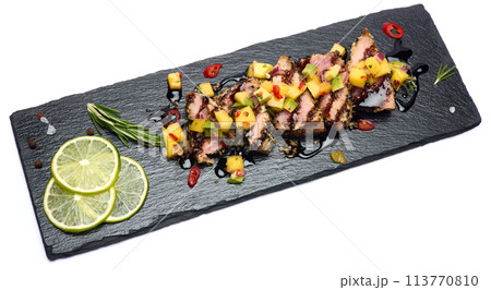 Sliced Organic grilled Tuna fillet covered with sesame seeds on black stone serving board 113770810