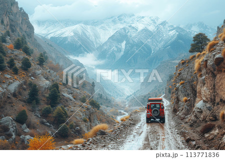 Red car on a mountain road amidst cliffs and autumn trees. 113771836