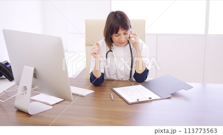 Doctor speaking on the phone celebrating a successful procedure Doctor speaking on the phone celebrating a successful procedure 113773563