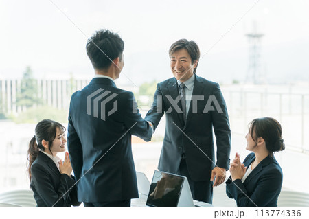 企業のオフィス・会議室で握手をして契約を結ぶビジネスマン 113774336