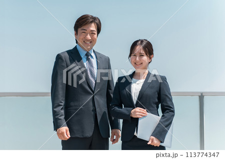 青空の下にいる経営者・社長の男性ビジネスマンと秘書の女性ビジネスウーマン 青空の下にいる経営者・社長の男性ビジネスマンと秘書の女性ビジネスウーマン 113774347
