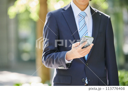 ビジネスイメージ スマホを持つスーツ姿の若い男性の手元 ビジネスイメージ スマホを持つスーツ姿の若い男性の手元 113776408