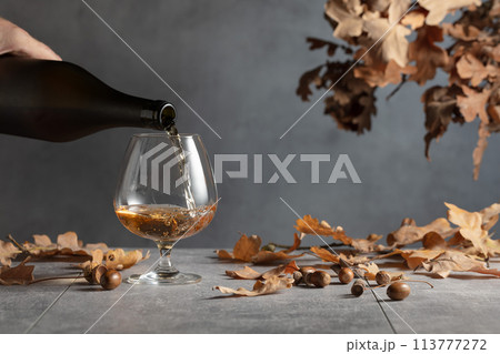 Brandy is poured from a bottle into a glass. 113777272
