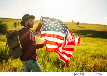 4th of July. American Flag.Patriotic holiday. Traveler with the flag of America. Beautiful sunset light. American style. 4th of July. American Flag.Patriotic holiday. Traveler with the flag of America. Beautiful sunset light. American style. 113777676