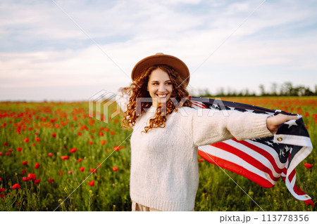 Young woman hold waving american USA flag in in the poppy field. Independence Day, 4th July. Young woman hold waving american USA flag in in the poppy field. Independence Day, 4th July. 113778356