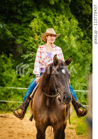 Cowgirl doing horse riding on countryside meadow Cowgirl doing horse riding on countryside meadow 113778437