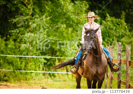 Cowgirl doing horse riding on countryside meadow Cowgirl doing horse riding on countryside meadow 113778439